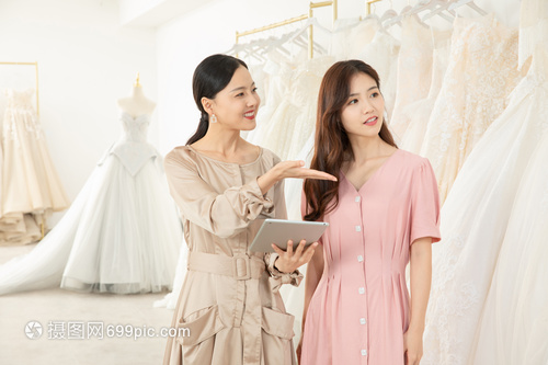 服務(wù)員使用平板電腦為顧客介紹婚紗
